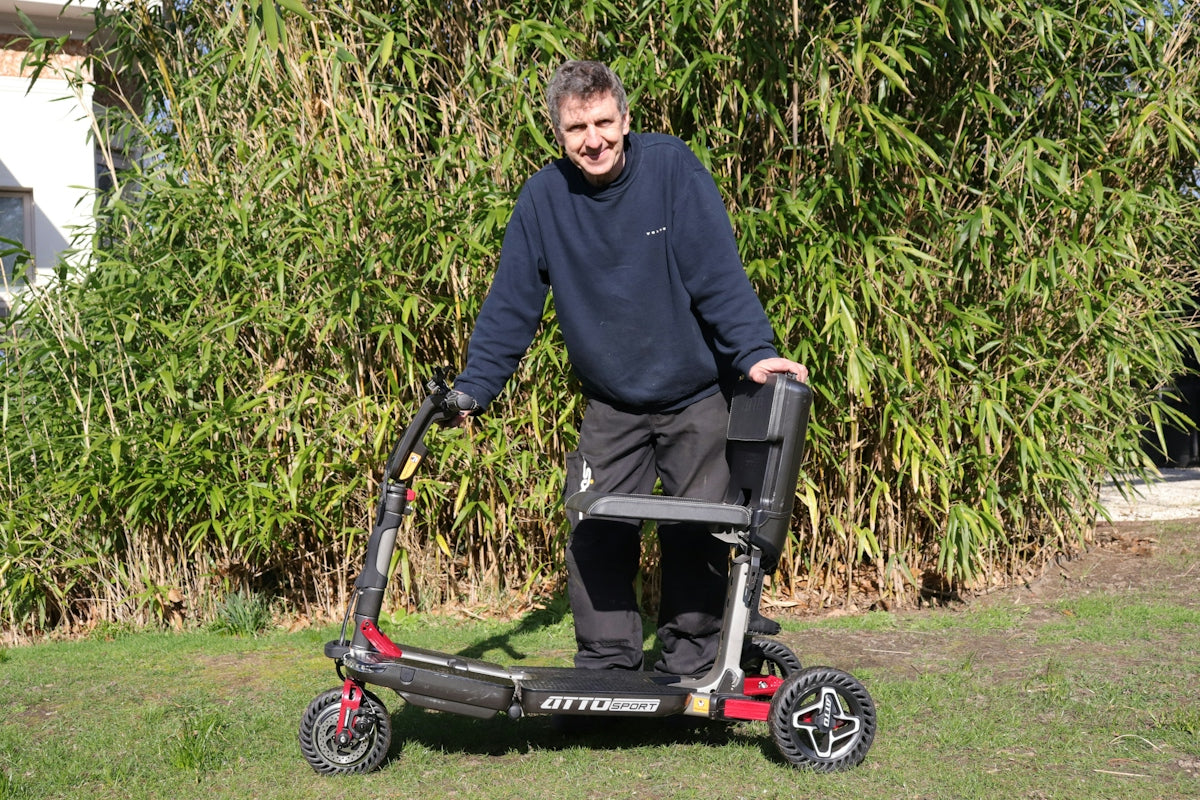 Man standing with a mobility scooter outdoors