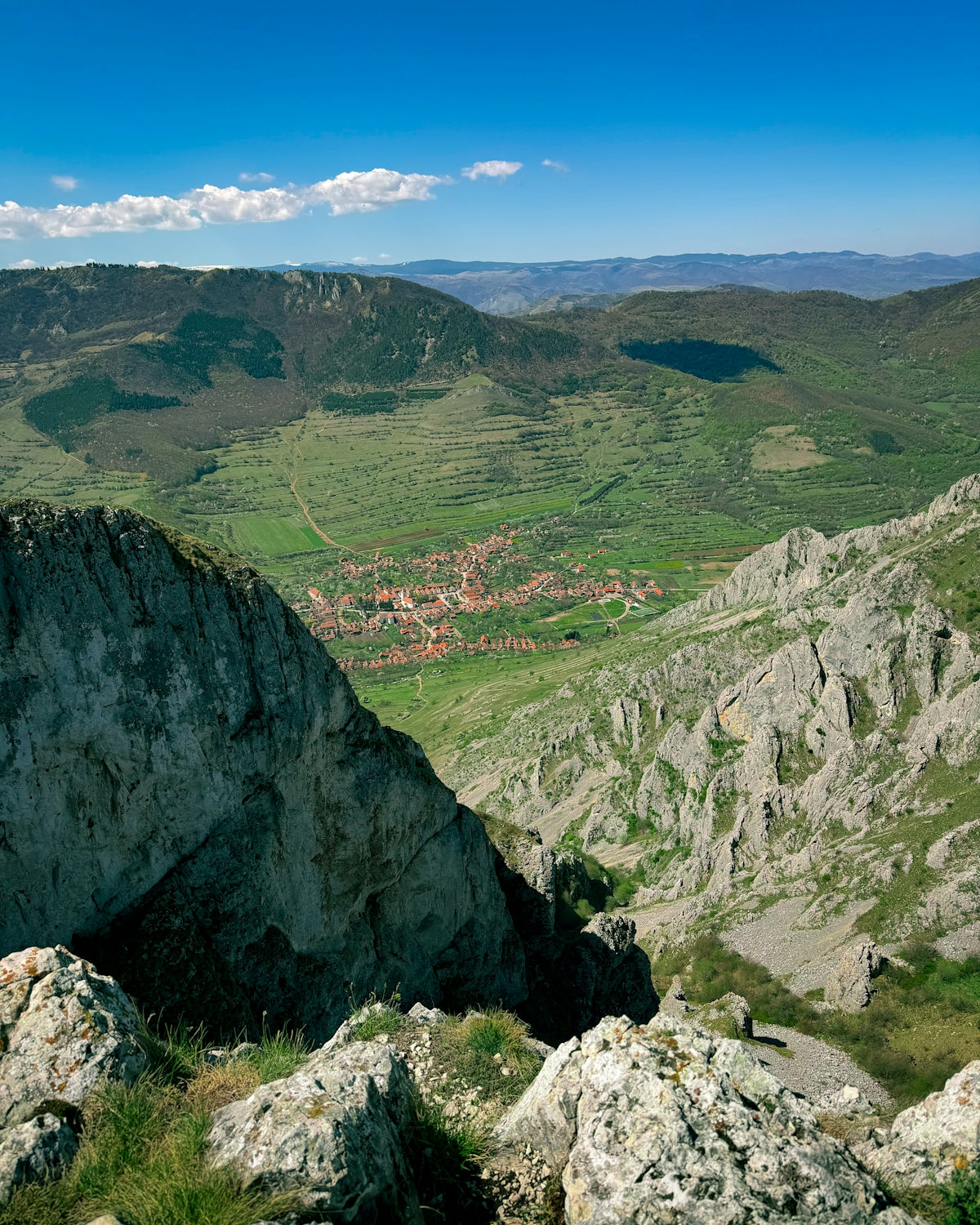 A village nestled in a green valley surrounded by mountains.