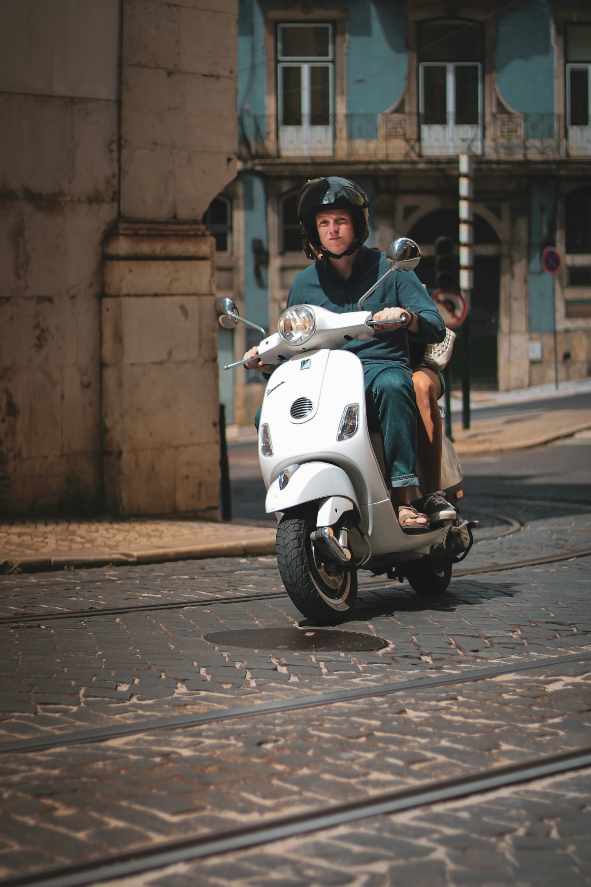 man in blue jacket riding white motor scooter