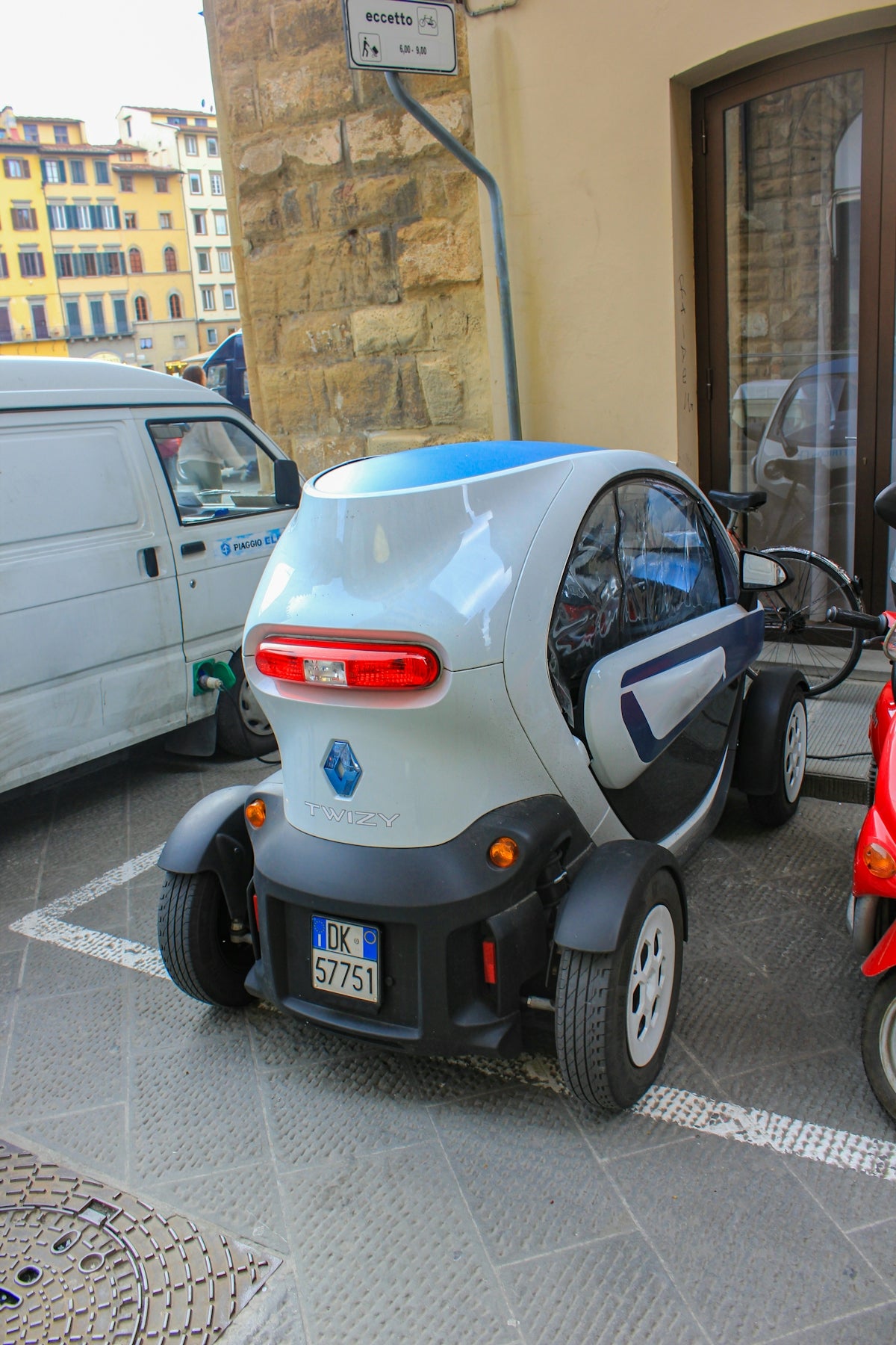 A person on a scooter next to a small car
