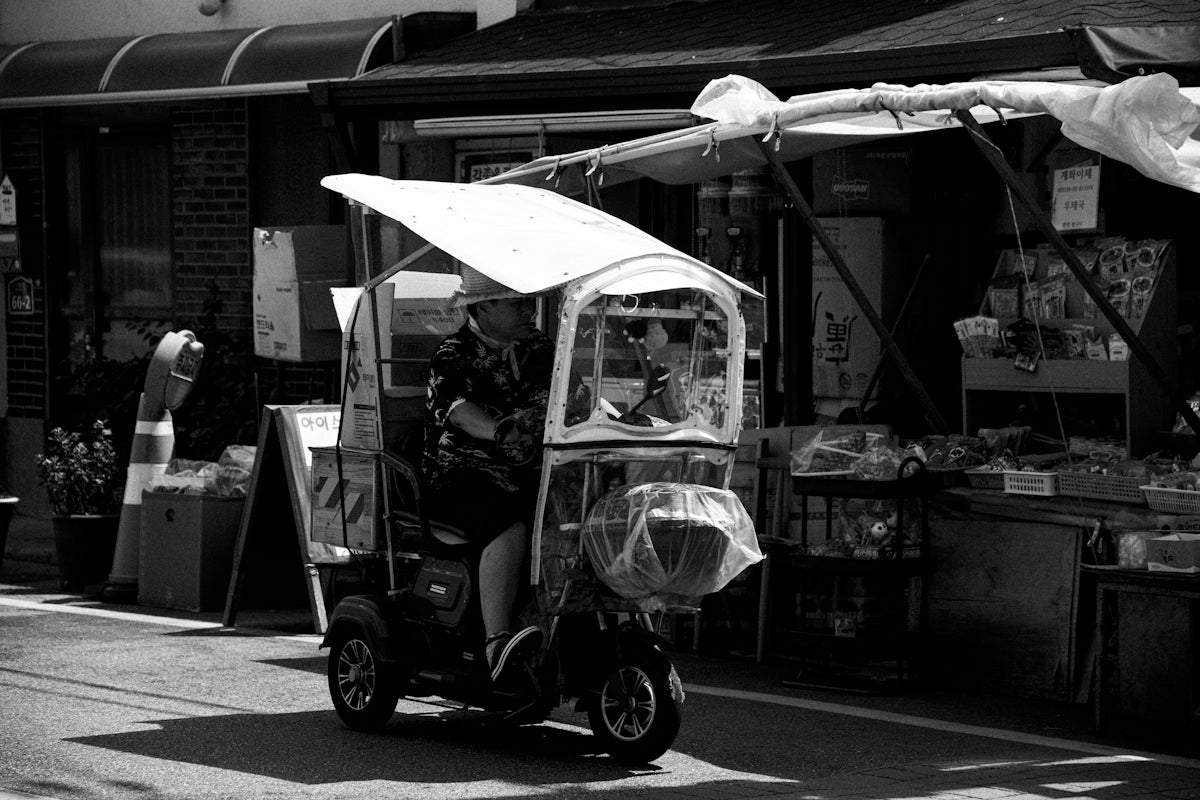 A person rides a covered scooter in the street.